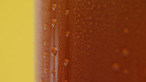 Close-Up-Of-Condensation-Droplets-Running-Down-Takeaway-Can-Of-Cold-Beer-Or-Soft-Drink-Against-Yellow-Background